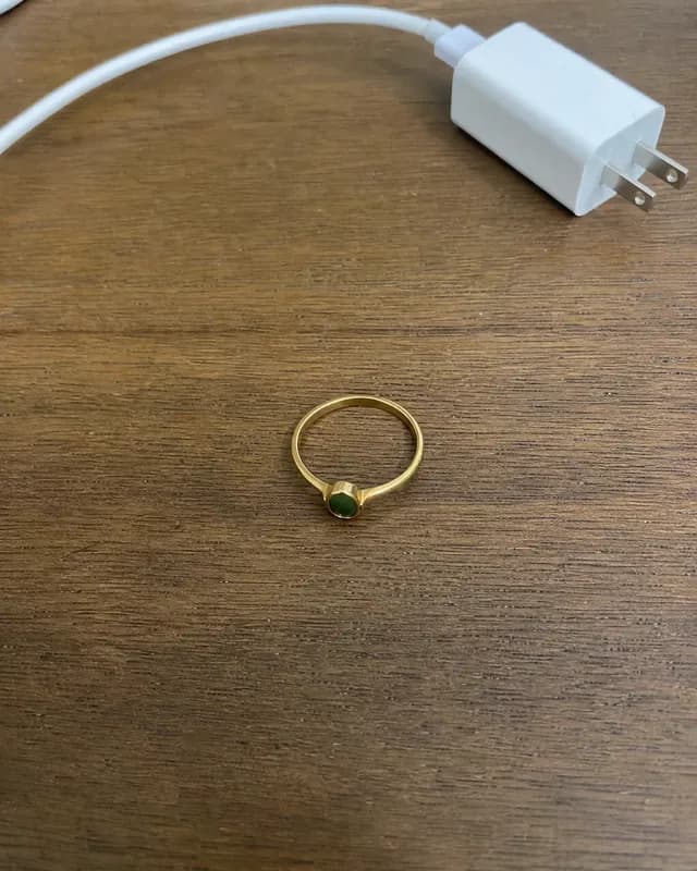 An example phone photo of a gold ring with a green stone